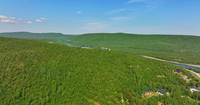 Drone rising over arctic hills, revealing the Teno river, in sunny Utsjoki, Finland