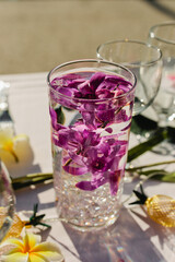 Glassware centerpiece at tropical party with purple orchids