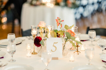 Table with floral centerpiece, candles, and table number five