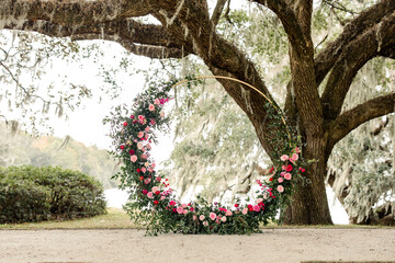 Circular floral arrangement with pink and red flowers under oak tree