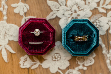 Wedding rings in red and teal velvet boxes on a lace background