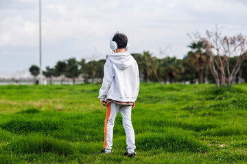 Young boy with headphones stands in the park