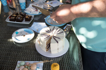 Cutting up a white birthday cake outside