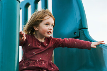 Little girl joyfully playing on a slide at the playground
