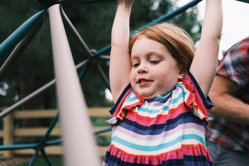 Young girl playing on jungle gym in a playground