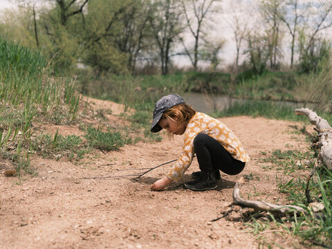 Child playing with sticks on a nature trail near a stream