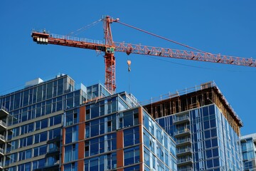 Towering crane on a bright day at an urban construction site with an emerging new building