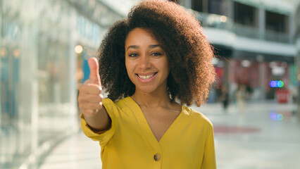 Young joyful African American woman showing thumb up smiling friendly female model gesture positive...
