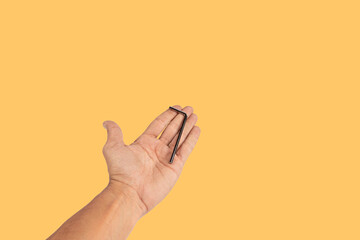 Black male hand holding an allen key isolated on yellow background