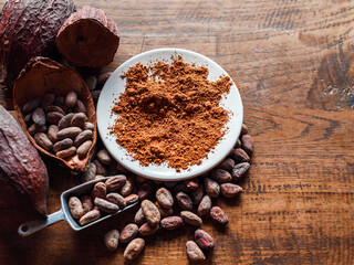 Top view of Natural cocoa powder with brown cocoa beans and dry cacao pod  on a vintage wooden table.