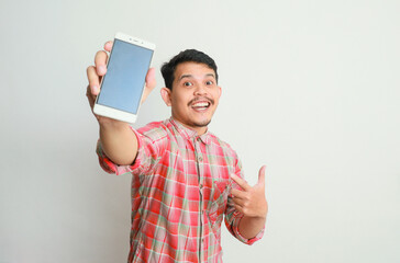 image of asian man holding phone, isolated on grey background. advertising concept.