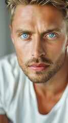 Fototapeta premium Handsome confident blond man, staring serious and cool at camera, wearing white t-shirt, white background