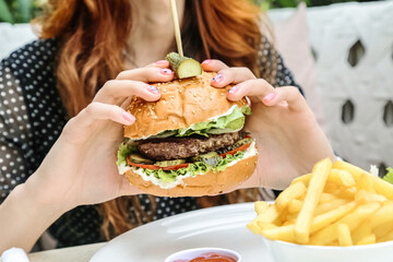 Woman Holding Hamburger and Fries in Front of Her Face