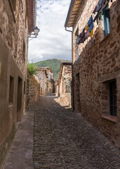 A narrow alley with a stone wall on each side. The alley is lined with houses and has a cobblestone