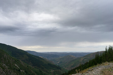The sky is cloudy and mountains are visible in the background. The mountains are covered with trees.