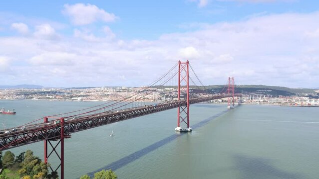 View of vehicles driving on 25 April Bridge crossing Tagus River on a sunny day, Portugal