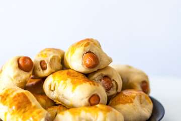 Sausages in the dough on ceramic plate on the table.