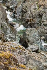 White river water rushing through colorful steep canyon walls and lichen covered rocks.