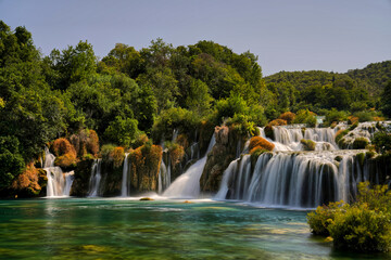 Obraz premium Waterfall cascading in lush forest with rocks and trees