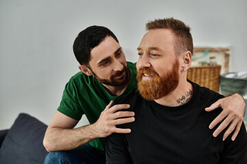 Obraz premium Two men, a loving gay couple, sit on a couch, enjoying a quiet moment together in their new home.