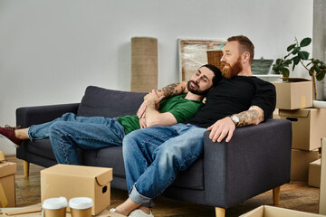 Gay couple in love sitting on couch, surrounded by packed boxes, starting new chapter in their life...