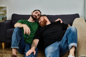 A loving gay couple sits on top of a couch in their new home