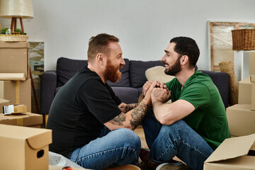 Two men in love, sitting amidst moving boxes, embracing each other in their new home.
