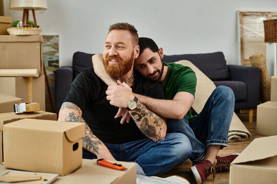 A gay couple in love, seated on boxes, embrace the start of a new life in their new home amidst the relocation process. - Powered by Adobe