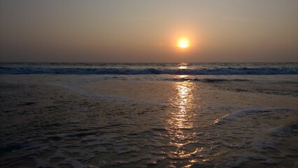 Beautiful sunset with the sun light reflecting from the sea water on the beach in Kerala, India