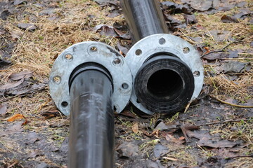 Unconnected black heavy-duty plastic pipes for water pumping with joints constructed of metal.