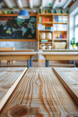A wooden desk in the foreground with a blurred background of a classroom. The background features student desks, a chalkboard or whiteboard, educational posters on the walls, and shelves.