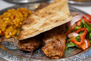 Grilled Turkish Adana, Urfa Kebab with grilled vegetables, onion and rice on plate. Adana durum. High quality photo
