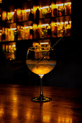 Glass of cocktail on a table with illuminated bottles in the background
