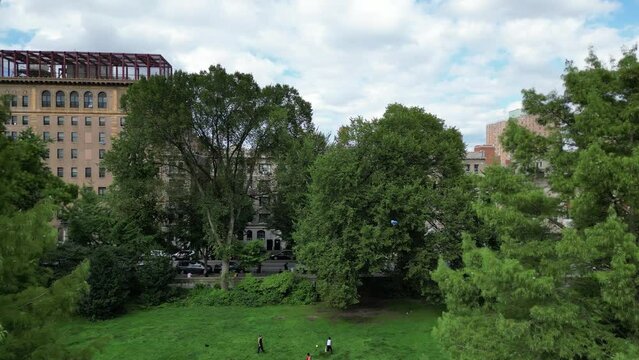 Ascending drone footage of people playing in East 110th Street Playground in daytime, USA