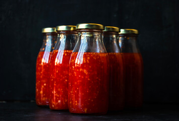 Bottles of bright orange sweet chili sauce over a dark black background.