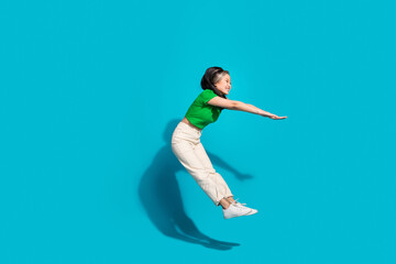 Full body portrait of pretty young girl jump fall empty space wear t-shirt isolated on turquoise...