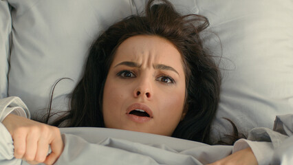Close up woman unhappy girl female looking duvet blanket open mouth frowning face surprised bed...