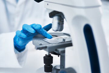 Hand, microscope and scientist in laboratory for research, experiment or pharmaceutical study. Science, innovation and closeup of medical researcher working with biotechnology equipment for discovery