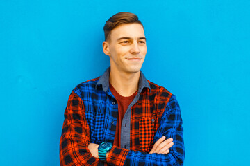 Happy handsome student man with hairstyle in fashionable shirt standing on blue background