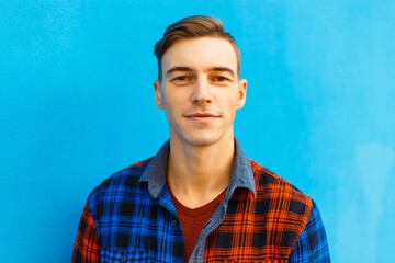 Cool fashion man with hairstyle in fashionable shirt on blue background