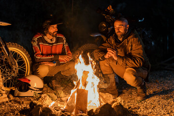 two men sitting next to each other near an open fire