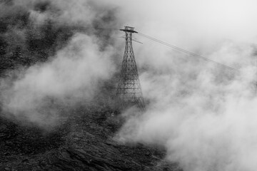 Fototapeta premium Transmission tower rises above a thick layer of low clouds at the summit