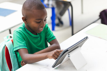 In school, young African American boy using a tablet in the classroom