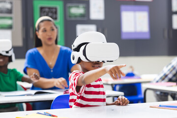 In school, in classroom, biracial female teacher watches students wearing VR headsets - Powered by Adobe