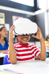 In school, young African American boy wearing a VR headset smiles in the classroom