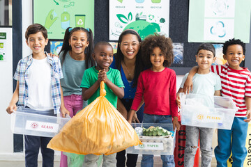 In school, diverse group of students and their teacher holding recycling materials in the classroom