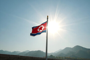 Fototapeta premium The national flag of North Korea waving in the wind with mountains in the background