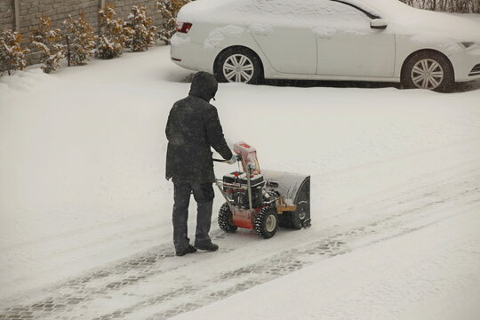 Robotnik clears snow from the sidewalk with a manual snowplow driven by a gasoline engine. Fighting the after-effects of a snowstorm. The power of the winter element