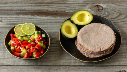 Pico de Gallo salsa, red corn tortillas, and avocado. Rustic wooden table. Healthy vegan Mexican food.