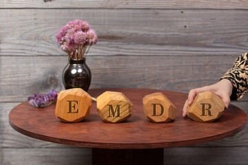 Letters EMDR written on irregular wooden blocks. A woman's hand adds the last block, Eye Movement...